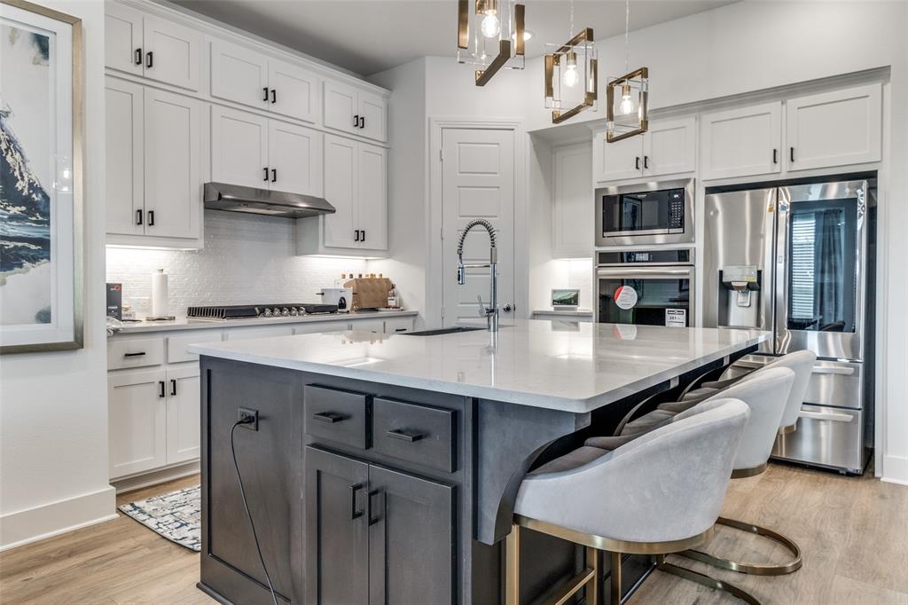 503 North Eagle Pt Road Van Alstyne, TX 75495 - Photo 5 of 25 Kitchen featuring white cabinetry, a kitchen bar, appliances with stainless steel finishes, light stone counters, and an island with sink