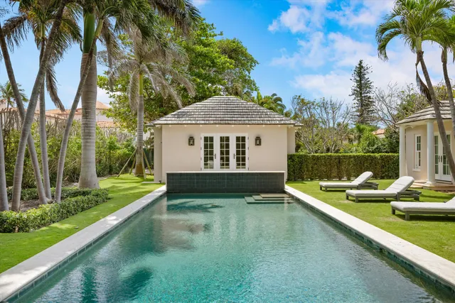 a view of swimming pool with chairs and palm trees