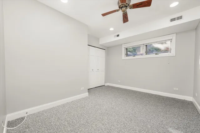 an empty room with windows and ceiling fan