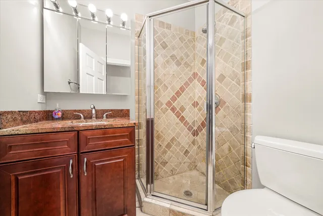 a bathroom with a granite countertop sink a toilet and shower