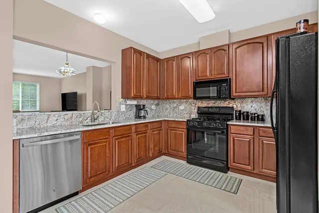 a kitchen with stainless steel appliances granite countertop a stove top oven a sink dishwasher a refrigerator and a microwave oven