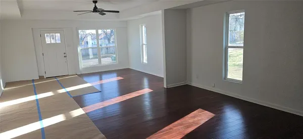 an empty room with wooden floor chandelier and windows