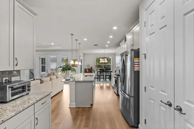 a kitchen with stainless steel appliances granite countertop a refrigerator oven a sink dishwasher and white cabinets with wooden floor