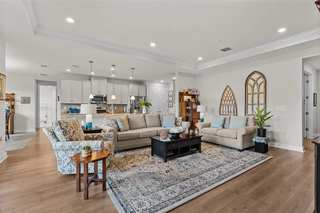 a living room with furniture kitchen view and a wooden floor