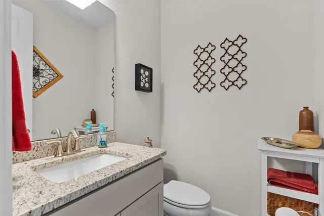 a bathroom with a granite countertop sink vanity mirror and toilet