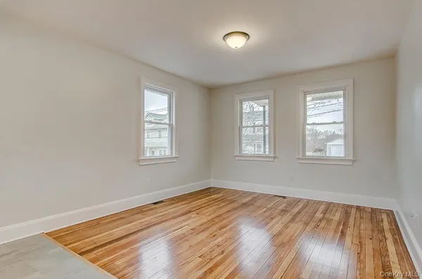 a view of empty room with window and wooden floor