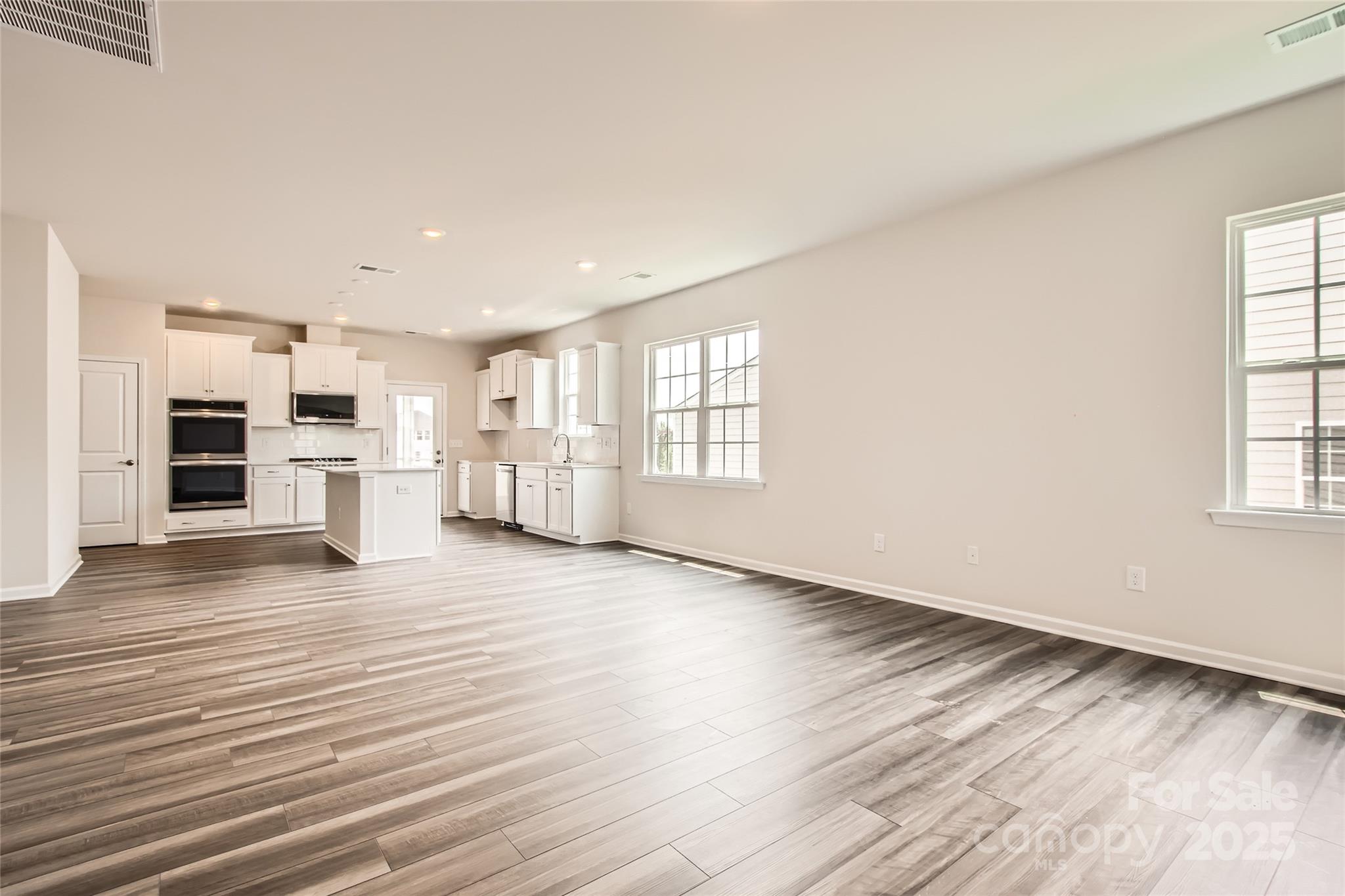 8473 Norman Frst Road Lancaster, SC 29720 - Photo 4 of 18 an empty room with wooden floor kitchen view and windows