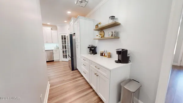 a large white kitchen with a sink a refrigerator and wooden floor