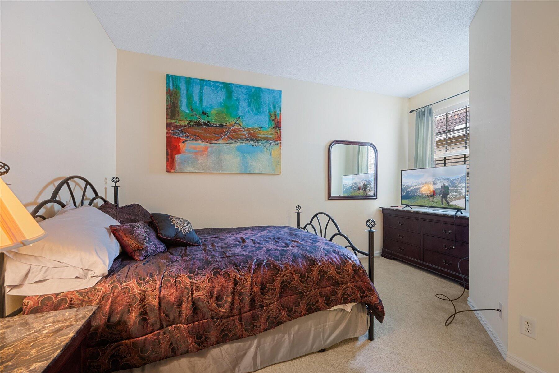112 Lighthouse Circle, Unit G Tequesta, FL 33469 - Photo 24 of 27 a bedroom with a bed and a painting on the wall