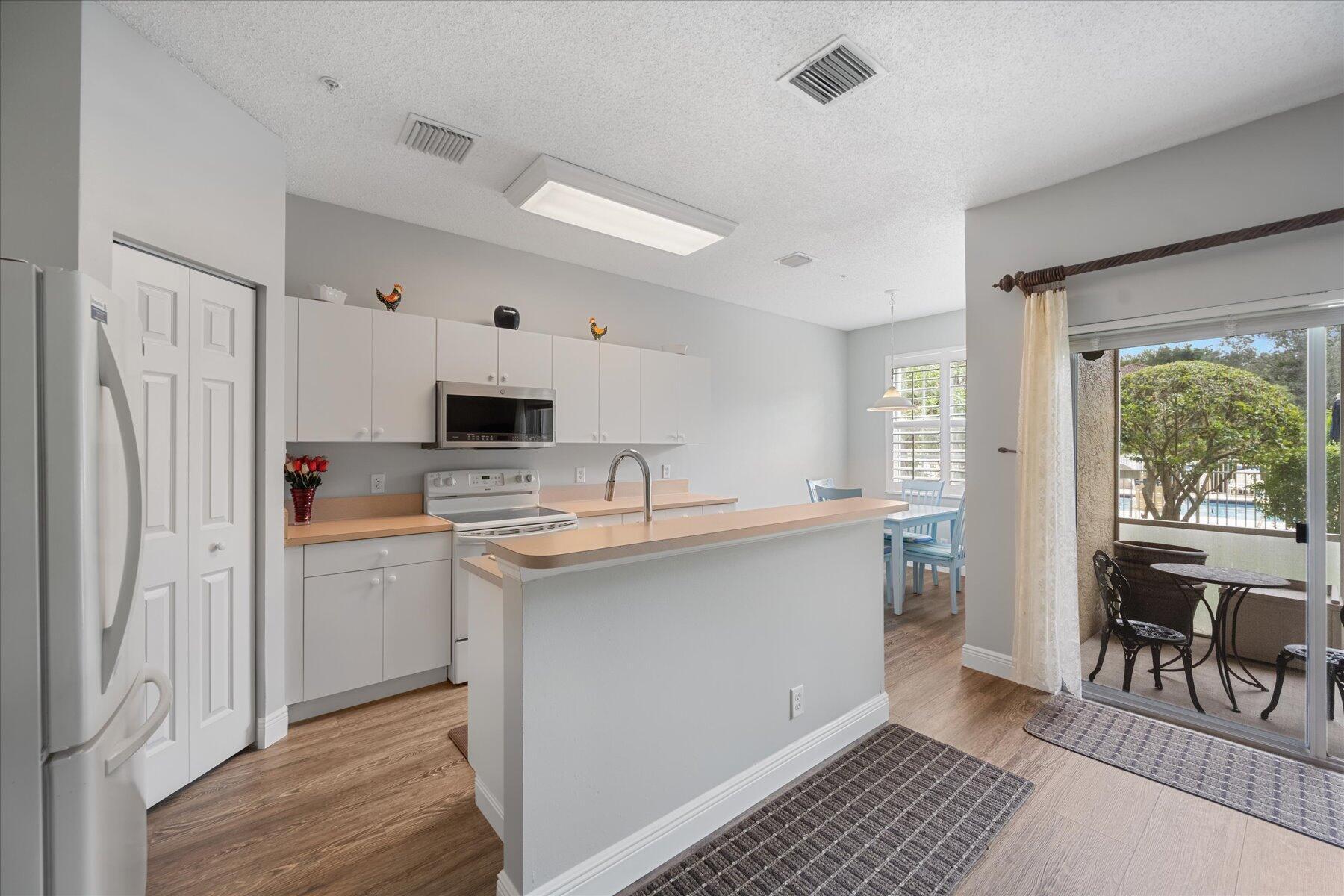 112 Lighthouse Circle, Unit G Tequesta, FL 33469 - Photo 8 of 27 a kitchen with a sink a counter top space stainless steel appliances cabinets and a window