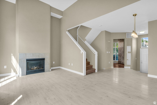 14108 Pepi Band Road Draper, UT 84020 - Photo 8 of 36 Living area featuring vaulted ceilings, wood-finish flooring, a tile-surround fireplace, and a multi-tiered staircase