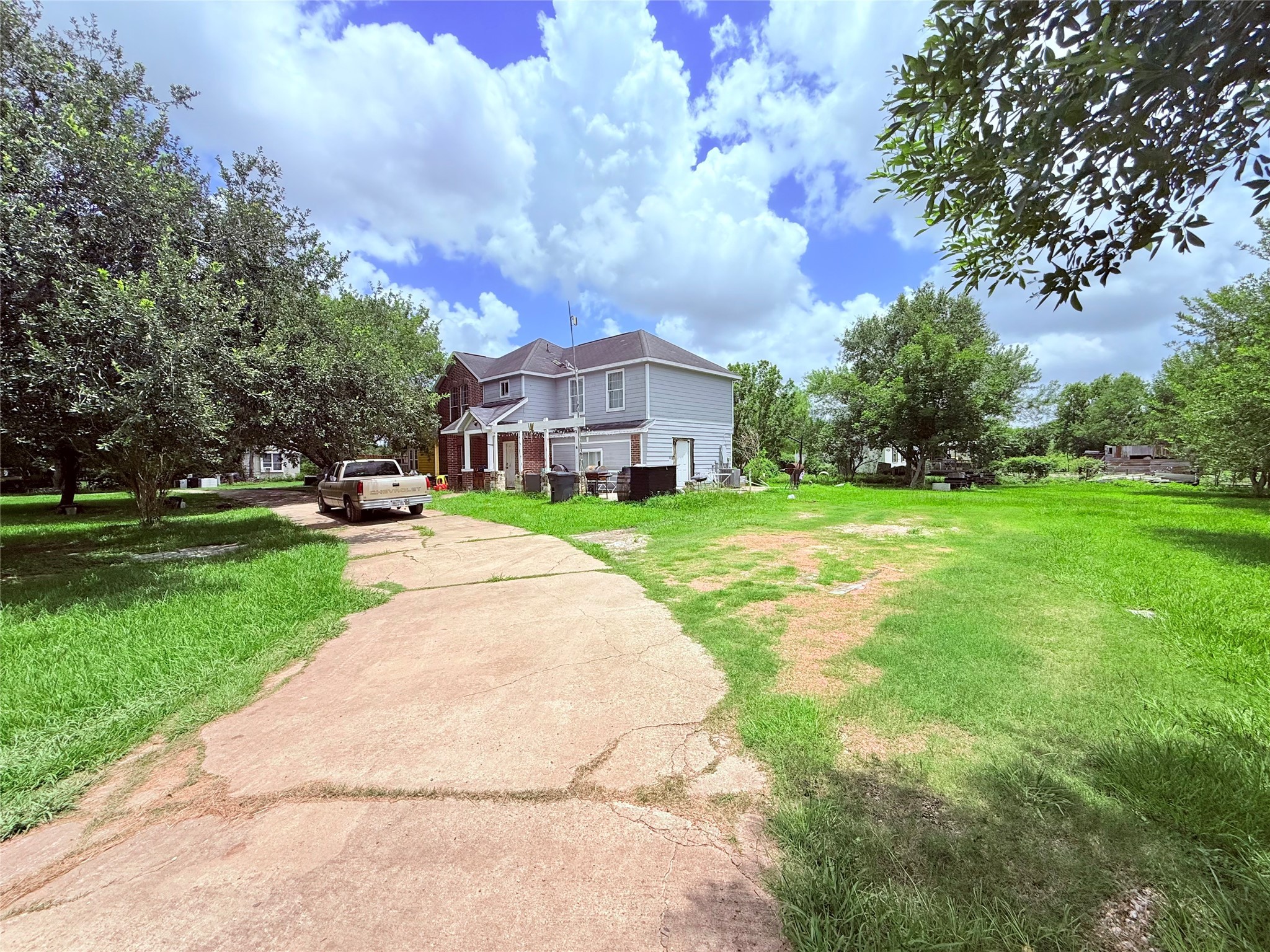 a view of a house with a big yard plants and large trees