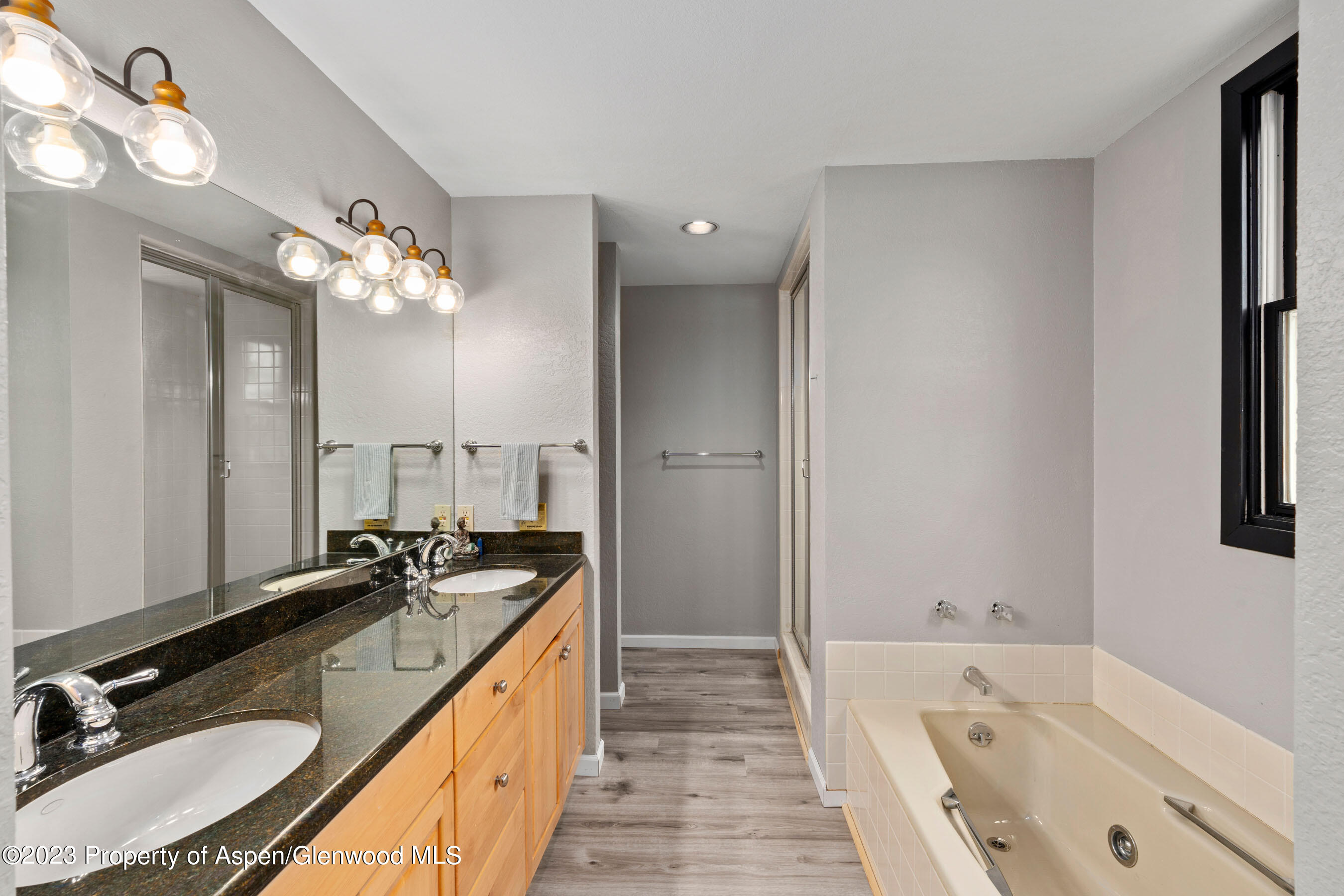 425 Wood Road, Unit 6 Snowmass Village, CO 81615 - Photo 19 of 29 a spacious bathroom with a granite countertop double vanity sink a mirror and a bathtub