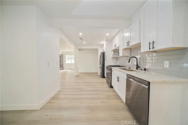 a large kitchen with stainless steel appliances granite countertop a sink and cabinets