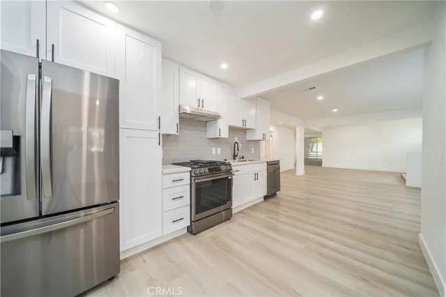 a large kitchen with stainless steel appliances a refrigerator and a stove top oven