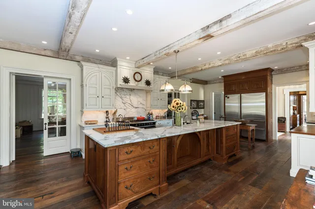 a kitchen with stainless steel appliances granite countertop a refrigerator a stove and a dining table with wooden floor