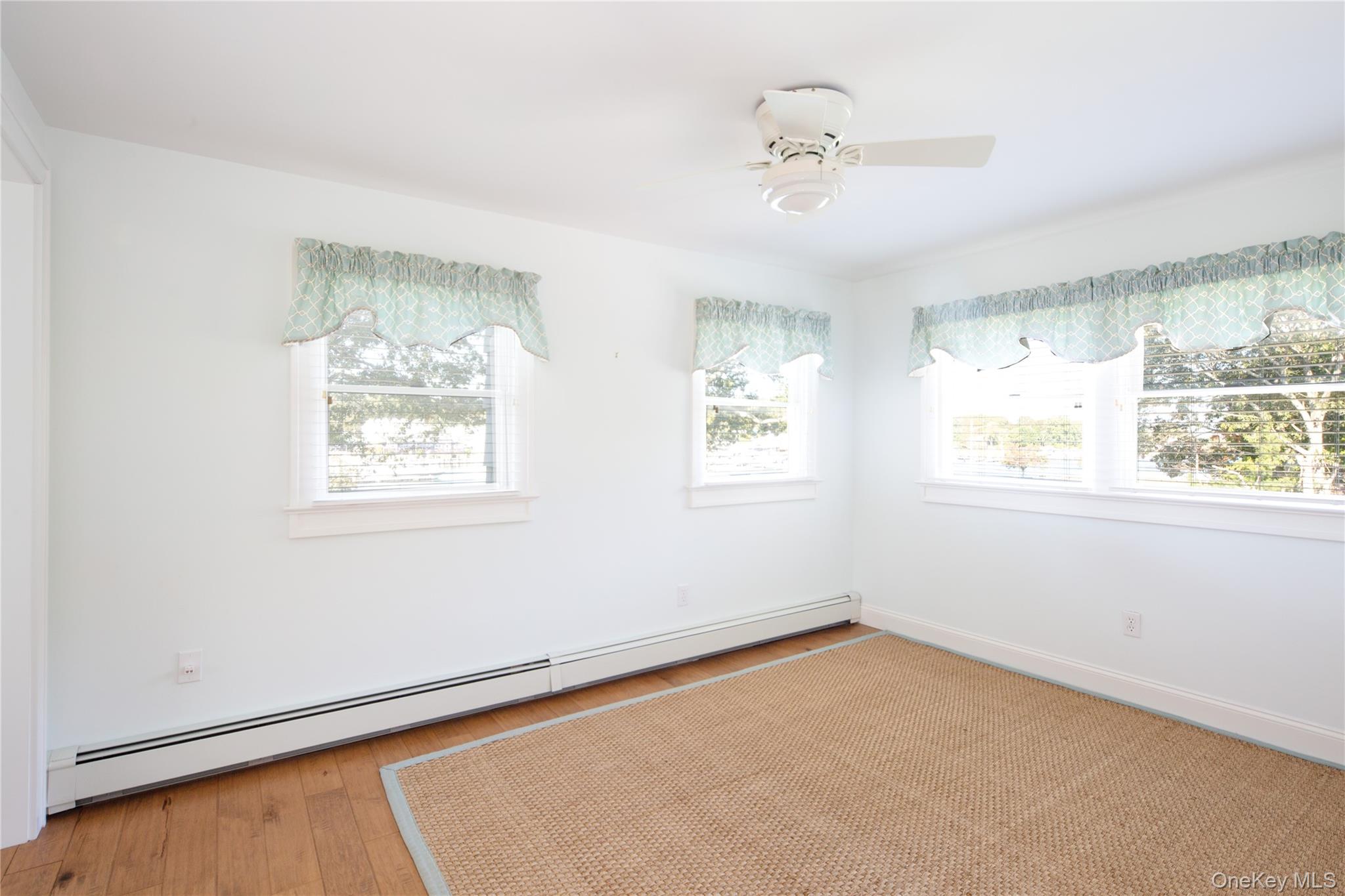 1 Canal Road Hampton Bays, NY 11946 - Photo 27 of 50 Spare room with baseboard heating, healthy amount of natural light, light wood-style flooring, and ceiling fan