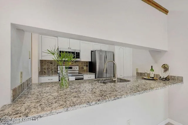 a kitchen with stainless steel appliances granite countertop a sink a stove and a refrigerator