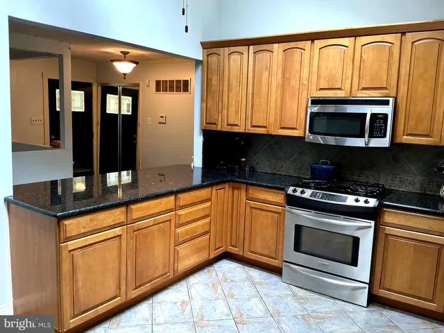 a kitchen with granite countertop a stove top oven microwave and cabinets