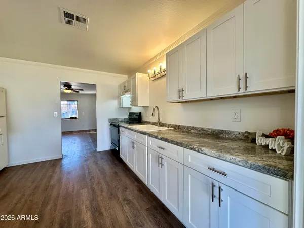 a kitchen with granite countertop a sink dishwasher stove and cabinets with wooden floor