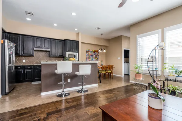 a kitchen with stainless steel appliances granite countertop a stove top oven a sink a dining table and chairs with wooden floor