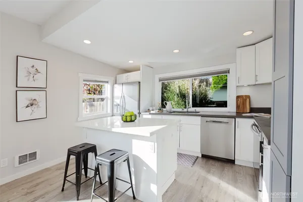 a kitchen with white cabinets and window