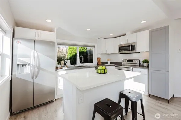 a kitchen with kitchen island a refrigerator stove microwave and cabinets