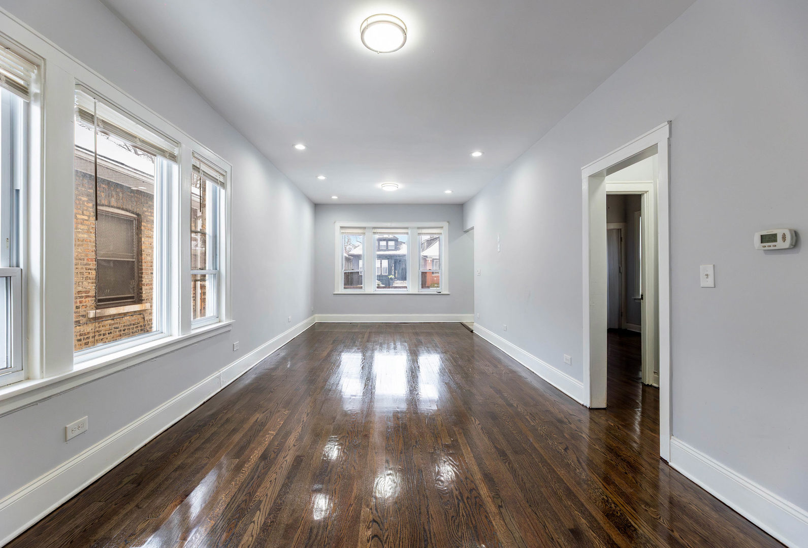 7427 South Perry Avenue Chicago, IL 60621 - Photo 3 of 19 a view of an empty room with wooden floor and a window