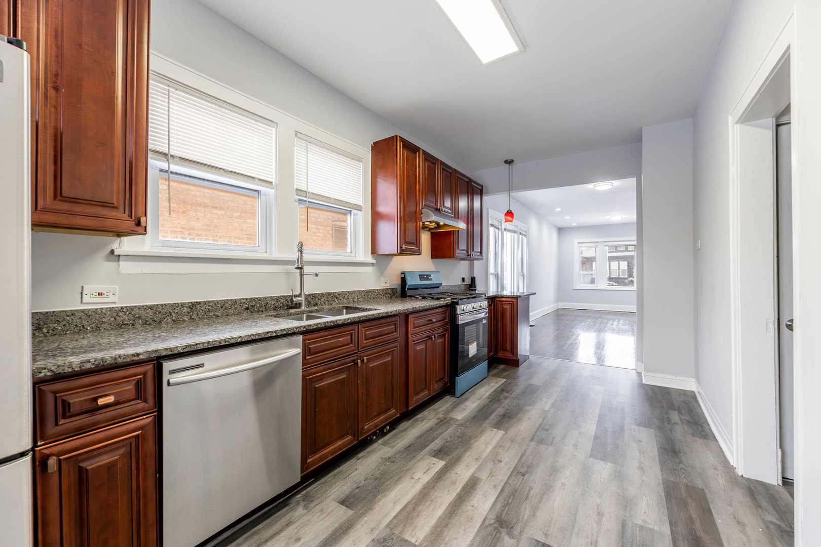 7427 South Perry Avenue Chicago, IL 60621 - Photo 7 of 19 a kitchen with stainless steel appliances granite countertop hardwood a kitchen island sink stove and wooden cabinets