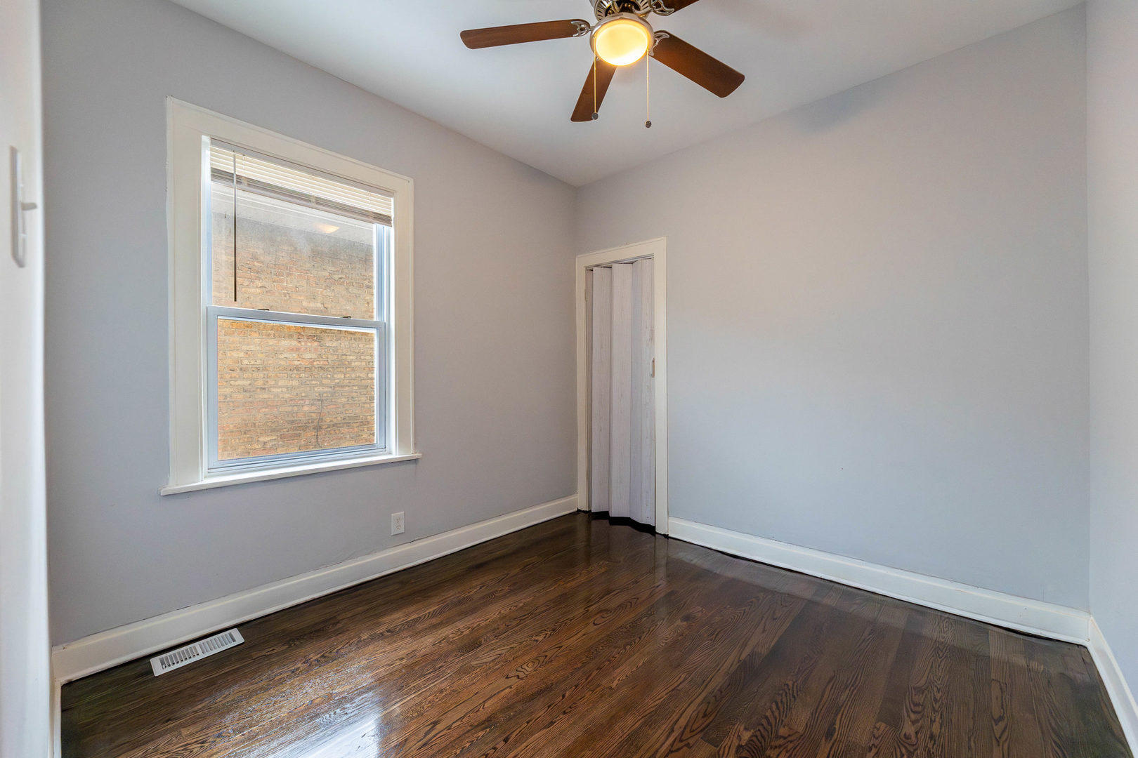 7427 South Perry Avenue Chicago, IL 60621 - Photo 9 of 19 an empty room with wooden floor fan and windows