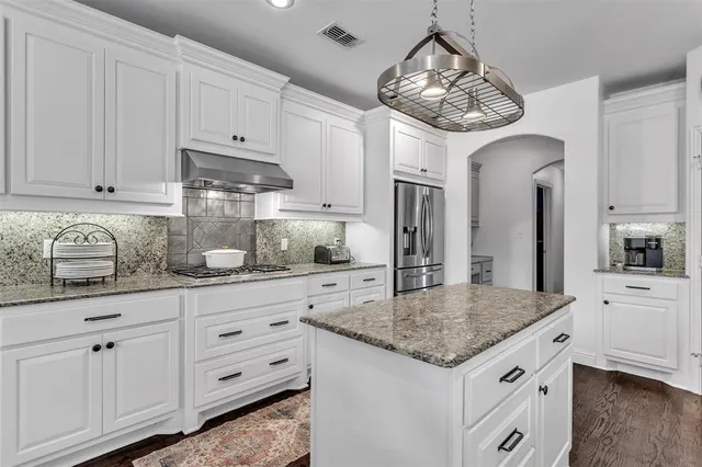 a kitchen with granite countertop white cabinets and chandelier