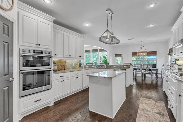 a kitchen with white cabinets stainless steel appliances and dining table view