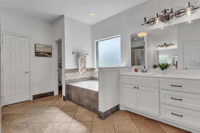 a spacious bathroom with a bathtub sink and mirror