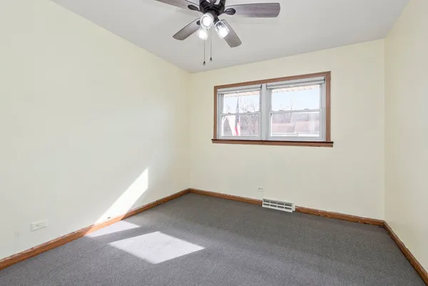 an empty room with a chandelier fan and closet