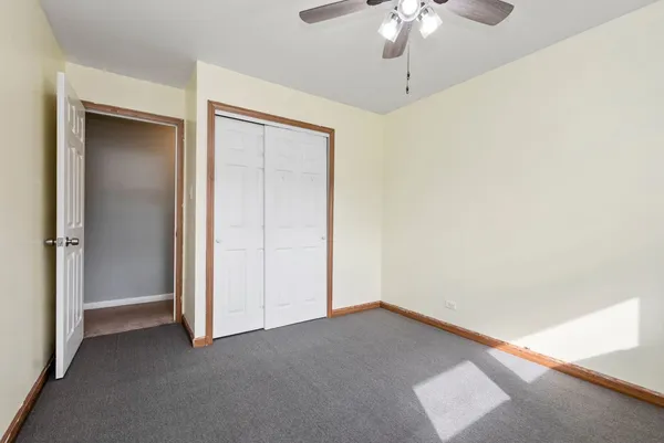 an empty room with a chandelier fan and windows