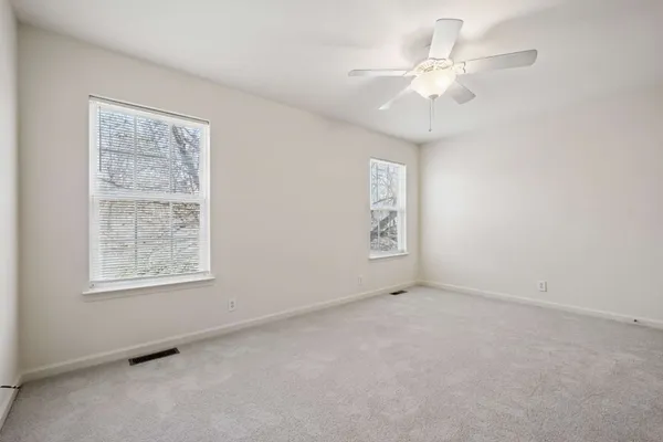 an empty room with windows and fan