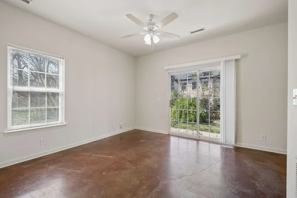 an empty room with windows and ceiling fan