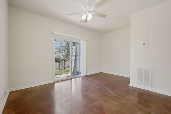 an empty room with windows and ceiling fan