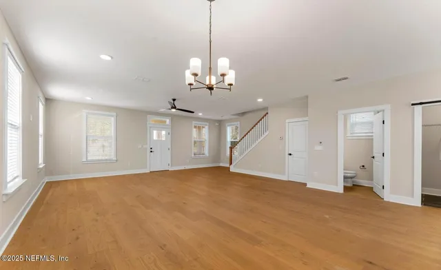 a view of a livingroom with a chandelier fan and windows