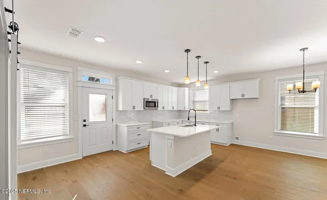 a large white kitchen with a stove a sink dishwasher and a refrigerator with wooden floor
