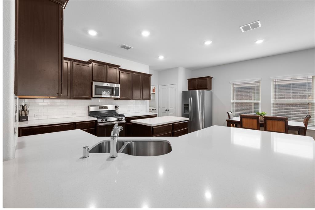 a kitchen with stainless steel appliances a sink a stove a microwave a refrigerator a window