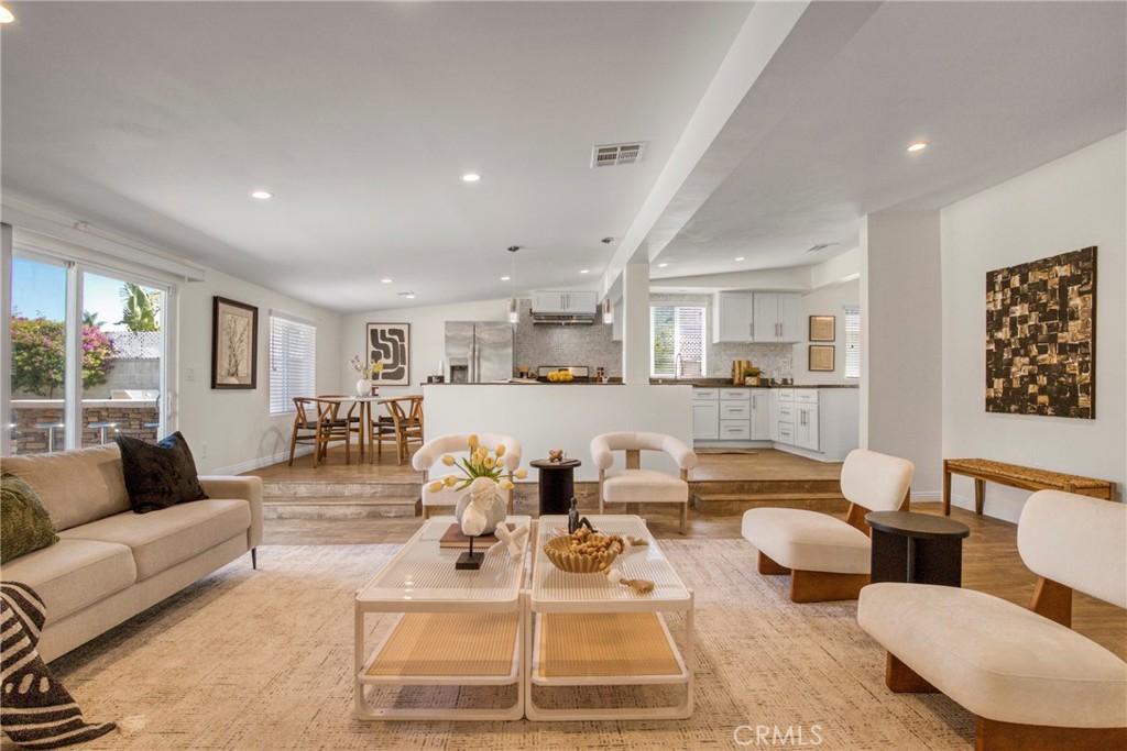 a living room with lots of white furniture and view of kitchen