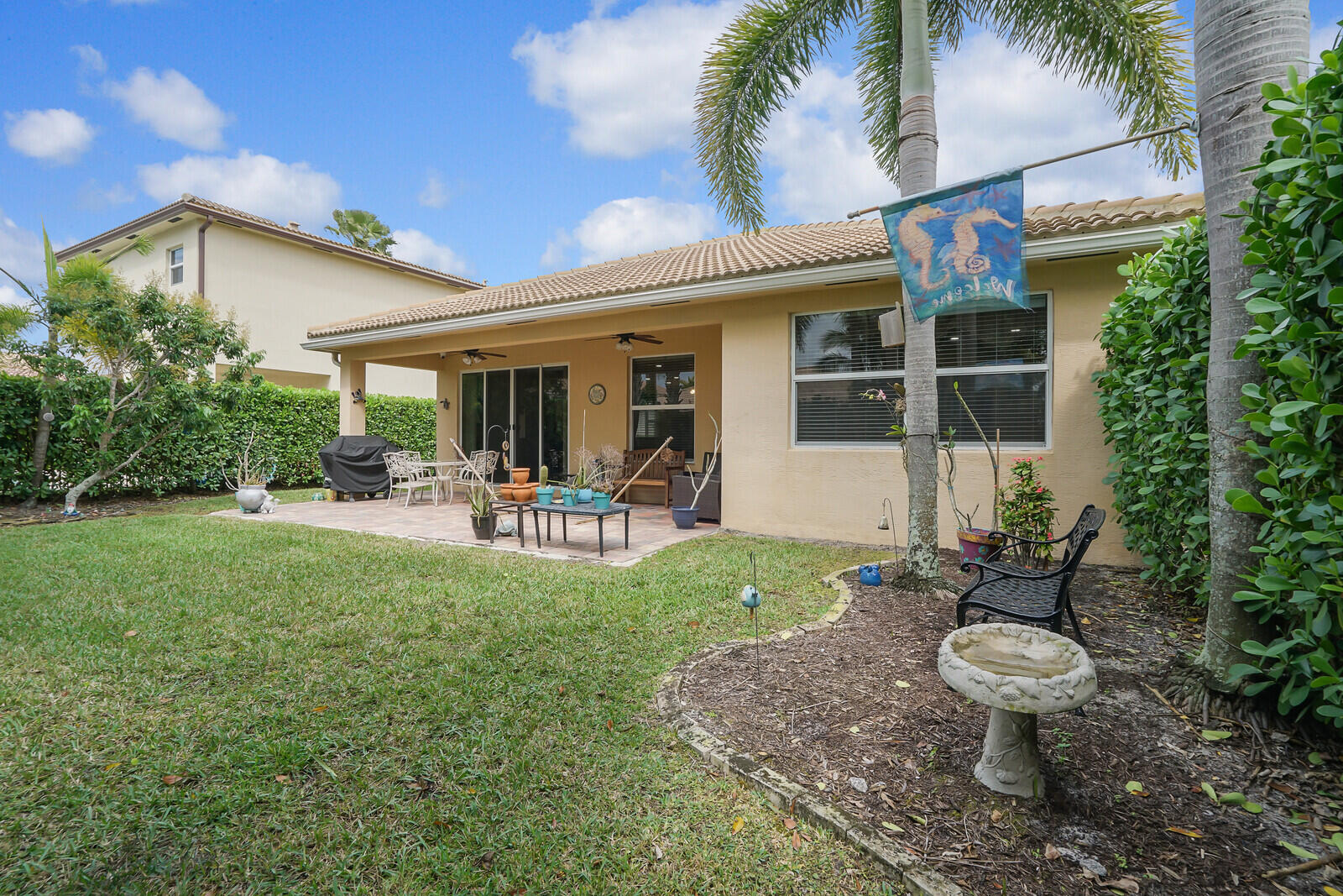 212 Behring Way Jupiter, FL 33458 - Photo 43 of 56 a view of a patio with table and chairs potted plants and palm tree