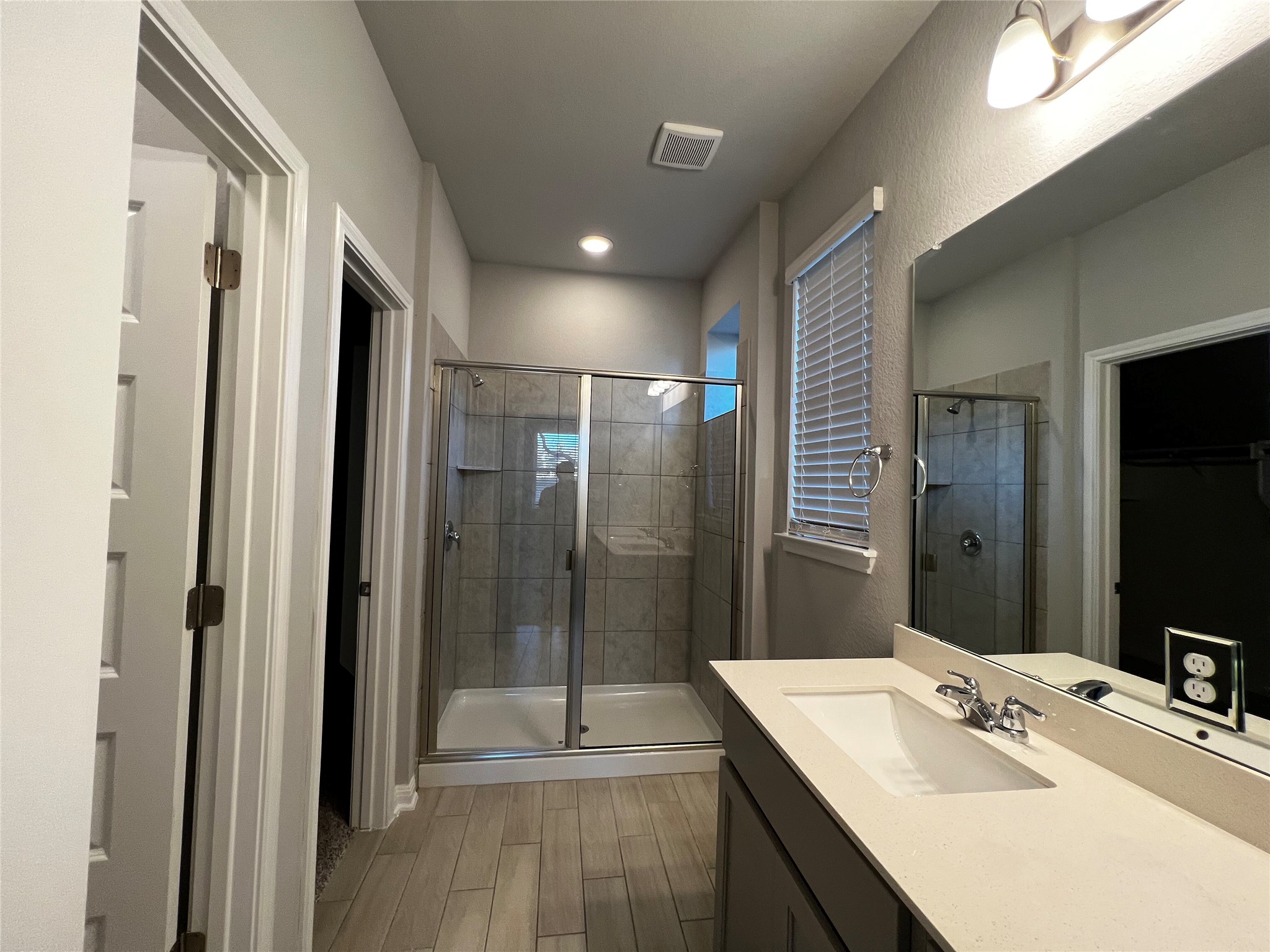 2720 Juniper Woods Road Leander, TX 78641 - Photo 3 of 8 The bathroom features a vanity with a light-colored countertop and an integrated sink, a large mirror, and a shower enclosure with a glass door and tiled walls