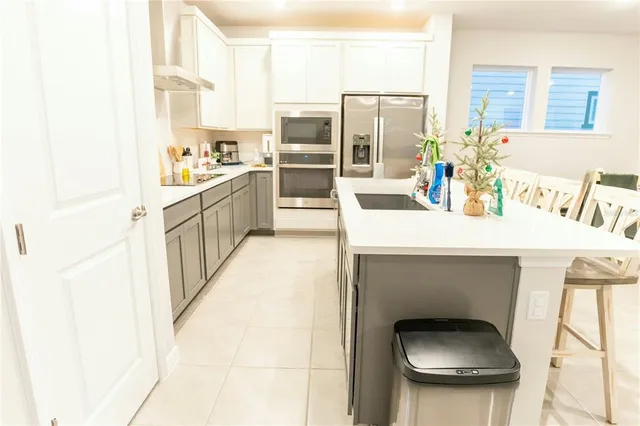 a kitchen with stainless steel appliances kitchen island granite countertop a sink refrigerator and cabinets