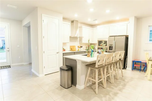 a dining hall with stainless steel appliances kitchen island granite countertop a sink and a refrigerator