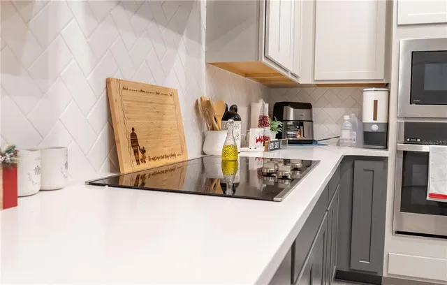 a kitchen with stainless steel appliances granite countertop a table chairs refrigerator and microwave