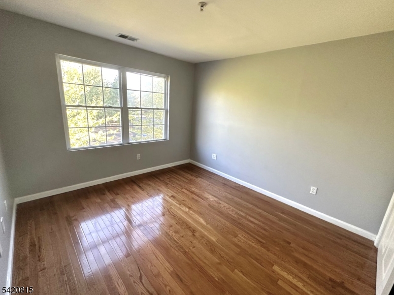 111 Harris Avenue, Unit 5 Middlesex, NJ 08846 - Photo 4 of 6 an empty room with wooden floor and windows