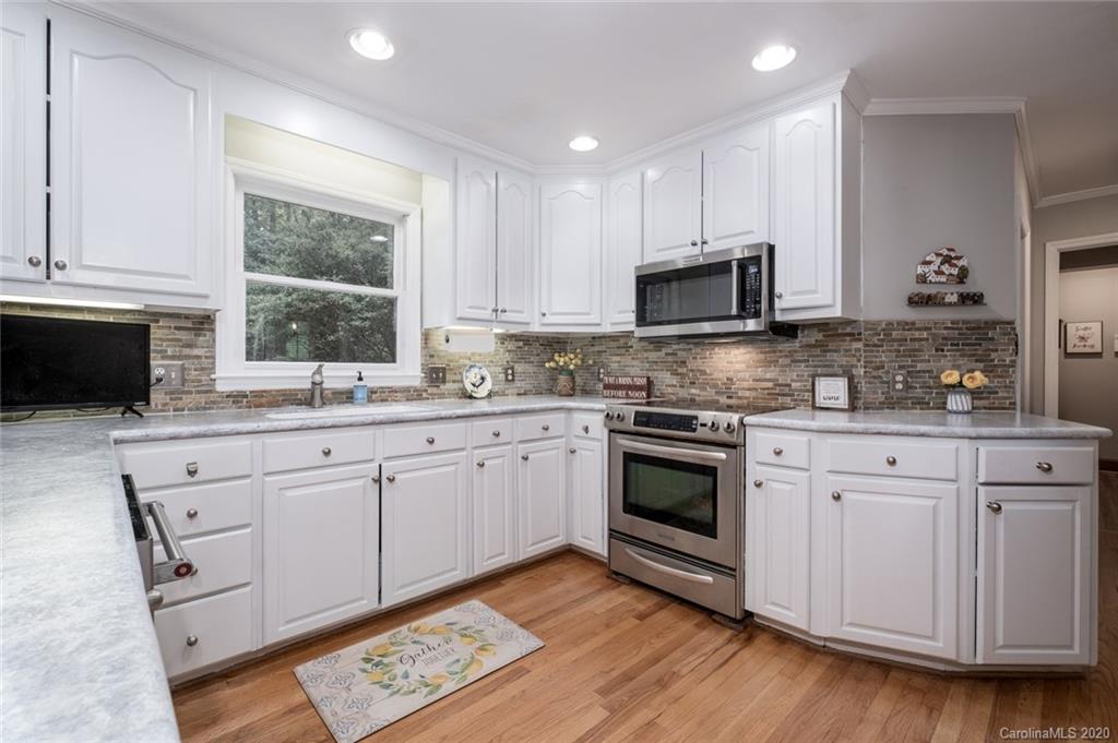 1130 Churchill Road Davidson, NC 28036 - Photo 10 of 38 a kitchen with granite countertop a stove a sink and a microwave