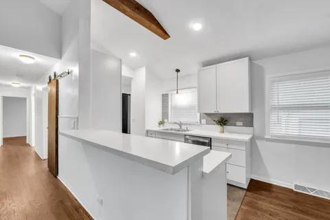 a large kitchen with a lot of counter space and wooden floor